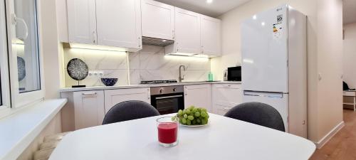 una cocina blanca con una mesa con una bebida. en Sonata apartment, en Panevėžys