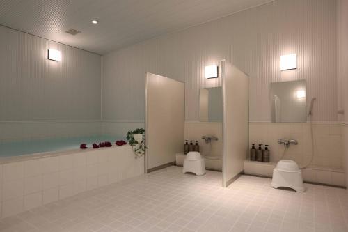 baño con 2 aseos y 2 lavabos y espejos en First Cabin Hakata, en Fukuoka