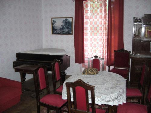 a room with a piano and a table and chairs at Kalmár Vendégház-Vadászház in Tornyiszentmiklós