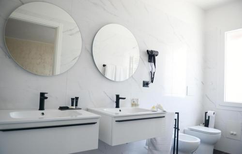 bagno con 2 specchi, lavandino e servizi igienici di B&B Riva del Gallo a Tresigallo