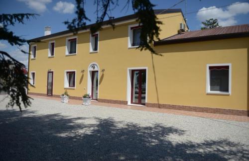 a yellow house with a driveway in front of it at B&B Riva del Gallo in Tresigallo