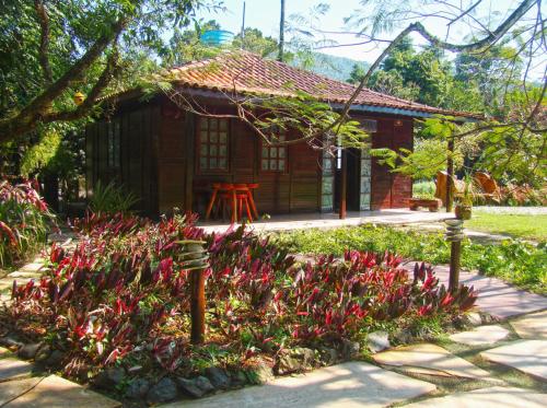 a small house with red flowers in front of it at Pousada Recanto das Aves in Iguape