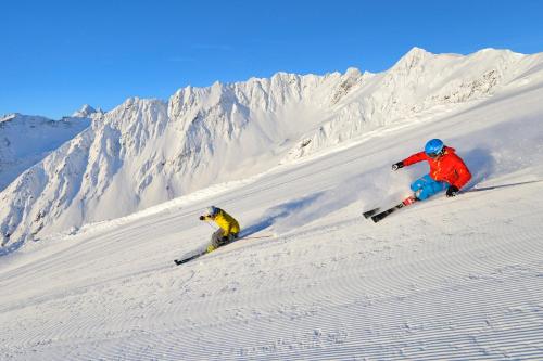 zwei Personen, die einen schneebedeckten Berg hinunter fahren in der Unterkunft Mountain alpine in Kappl