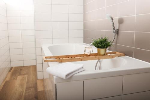 a white bathroom with a tub and a plant on a counter at Heeren aan de Haven in Streefkerk