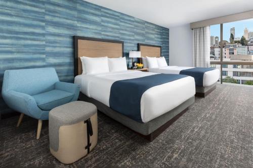 a hotel room with two beds and a chair at Hotel Caza Fisherman's Wharf in San Francisco
