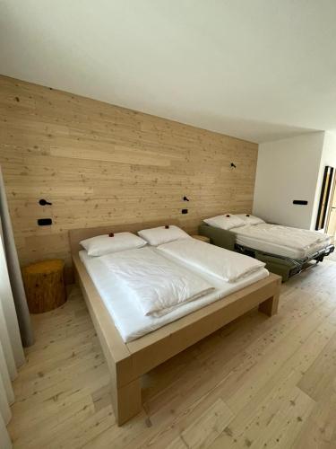 two beds in a room with a wooden wall at Penzion Kolnička in Luka nad Jihlavou