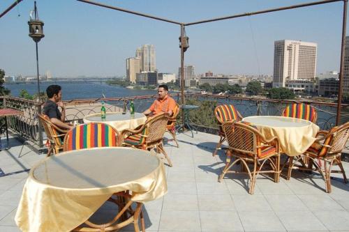 two men sitting at tables on a balcony at Nile Zamalek Hotel in Cairo