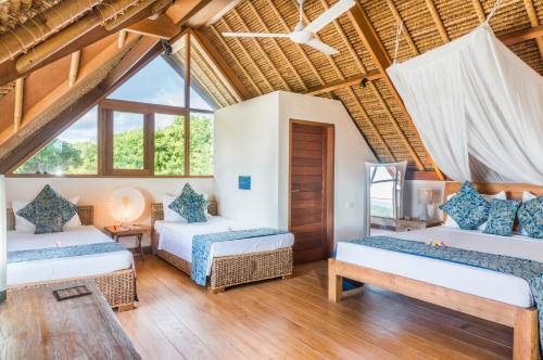 a room with three beds and a window at Villa Nusa in Nusa Lembongan