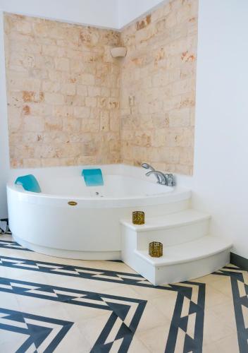a bath tub in a bathroom with a tile floor at Villa Aurelia Suites and Apartments in Locorotondo
