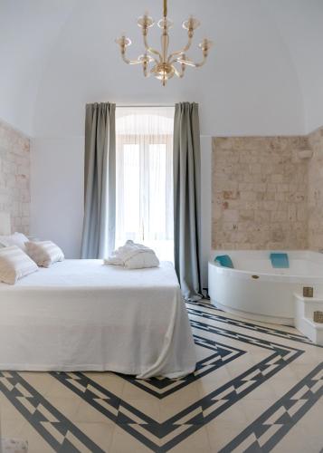 a bedroom with a bed and a bath tub and a chandelier at Villa Aurelia Suites and Apartments in Locorotondo