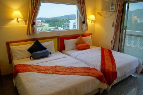 墾丁的住宿－墾丁福樂渡假旅店，配有窗户的酒店客房内的两张床
