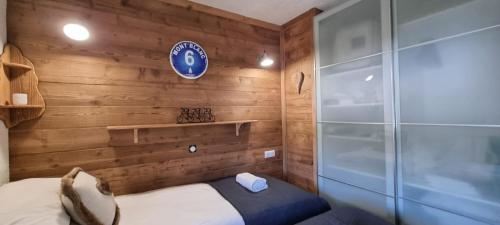 ein Schlafzimmer mit Holzwänden und ein Bett in einem Zimmer in der Unterkunft Luxury Central Apartment MONTCHAVIN in Bellentre