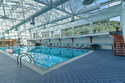 a large swimming pool in a building at Mercure Medias Binderbubi Hotel And Spa in Mediaş