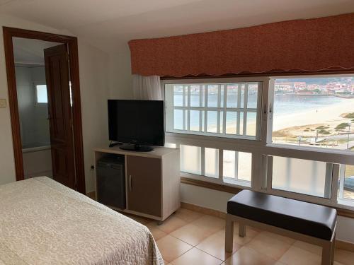 a bedroom with a bed and a television and windows at Hotel Playa in Cangas de Morrazo