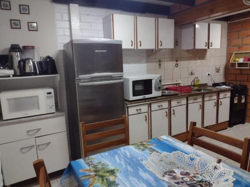 eine Küche mit einem Kühlschrank und einem Tisch darin in der Unterkunft Apartamento estilo chalé - Enxaimel in Bombinhas