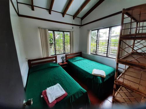 2 Betten in einem Zimmer mit 2 Fenstern in der Unterkunft Iguana Libre in Dominical