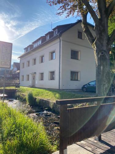 a white building with a tree in front of it at Mezonetový apartmán ve skandinávském stylu in Rokytnice nad Jizerou