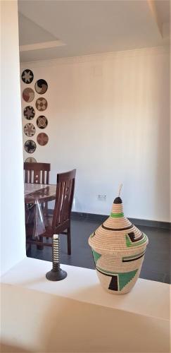 a vase sitting on a table next to a table at Isaro House Kigali in Kigali