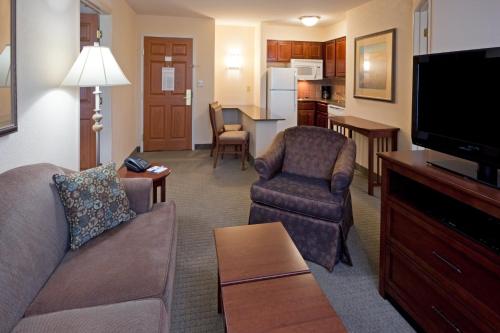 a living room with a couch and chairs and a kitchen at Staybridge Suites - Philadelphia Valley Forge 422 by IHG in Royersford