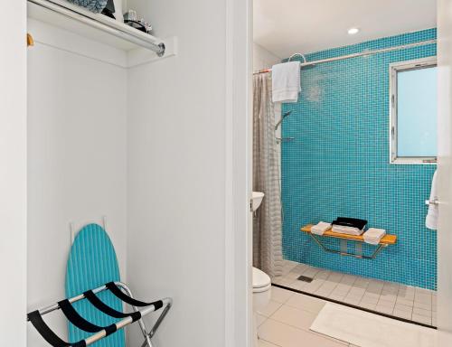 a bathroom with a blue tiled shower and a chair at The Twist Palm Springs in Palm Springs