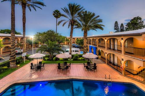 a swimming pool with tables and umbrellas in front of a building at Sleep Inn Monterrey Norte in Monterrey