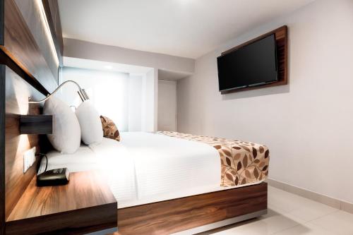 a bedroom with a bed and a flat screen tv at Sleep Inn Monterrey Norte in Monterrey