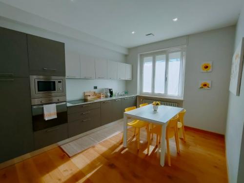 a kitchen with a white table and yellow chairs at Apartment AL34 in La Morra