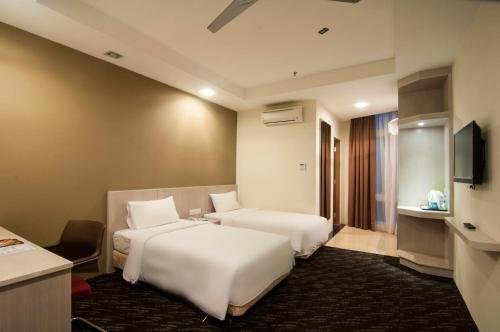 ein Hotelzimmer mit zwei Betten und einem Fernseher in der Unterkunft Scott Hotel KL Sentral in Kuala Lumpur