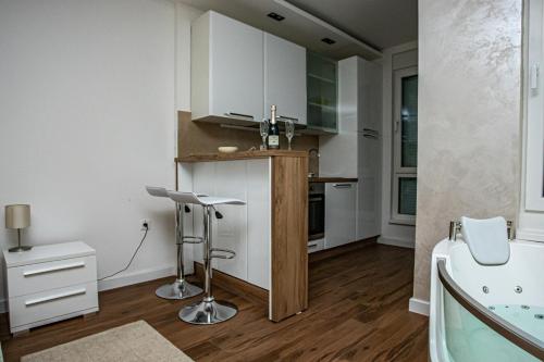 - une cuisine avec des placards blancs et un évier dans l'établissement Jacuzzi Lux Apartman, à Subotica