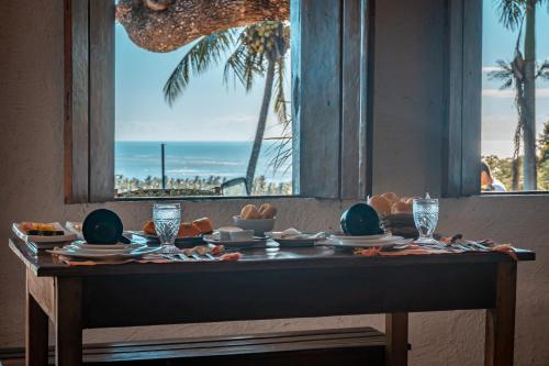 a table with a view of the beach from a window at Pousada Anacã in Arraial d'Ajuda