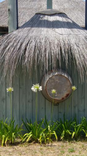a hut with a grass roof and some flowers at Cabañas Las Achiras in Punta Del Diablo
