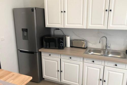 a kitchen with a stainless steel refrigerator and white cabinets at Les Jardins Des Chambrettes in Clermont-Ferrand