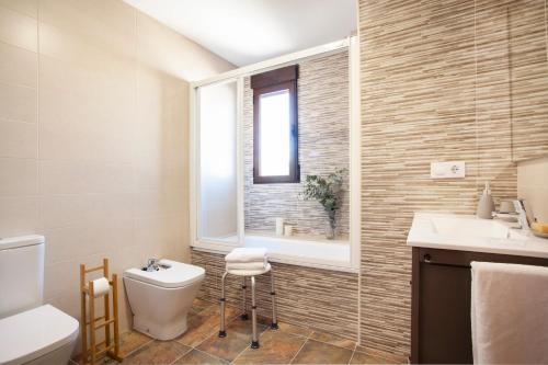 a bathroom with a toilet and a sink and a window at Casa rural Torre Buena Vista a 40 minutos de Valencia con gran jacuzzi y vistas maravillosass in Benafer