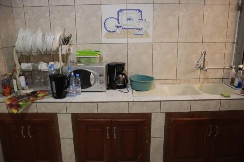 a kitchen counter with a sink and a microwave at Résidence Jeanne à Yaoundé Odza Messamengo in Yaoundé