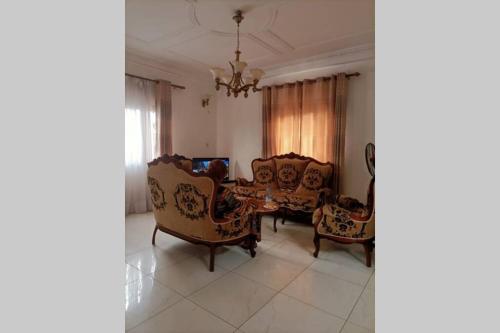 a living room with chairs and a table and a chandelier at Résidence Jeanne à Yaoundé Odza Messamengo in Yaoundé