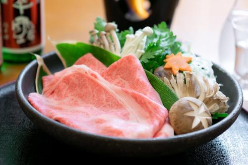 a bowl filled with meat and vegetables on a table at Okushiga Kogen Hotel in Yamanouchi