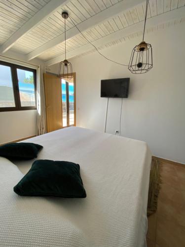 een slaapkamer met een wit bed met 2 kussens erop bij Casa Kiko Fuerteventura in Cotillo