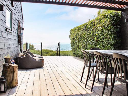 a wooden deck with a table and chairs and the ocean at 4 person holiday home in S nder Stenderup in Sønder Stenderup