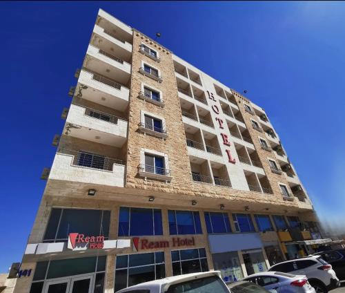 un edificio alto con coches estacionados en un estacionamiento en Ream Hotel Amman en Amán