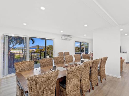 a dining room with a long table and chairs at Island View Large Family Home Pool WI FI and Sweeping Views of Fingal in Fingal Bay