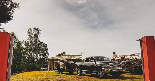 a black truck parked in a field with a trailer at Pousada Pato Mergulhão in Vargem Bonita