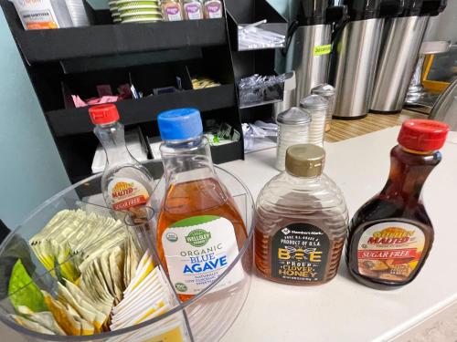 a counter with a bunch of bottles of sauce at Ocean Sands Beach Boutique Inn-1 Acre Private Beach-St Augustine Historic-2 Miles-Shuttle with Downtown Tour-HEATED Salt Water Pool until 420AM-Popcorn-Cookies-New 4k USD Black Beds- 69 Item Breakfast-Eggs-Bacon-Starbucks- Free Laundry- #904-799-SAND in Saint Augustine