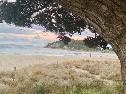 a person walking on a beach near the ocean at Modern Beach Apartment with Pool & Location in Mount Maunganui