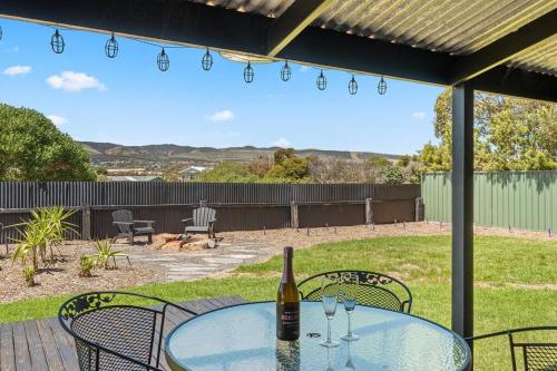 einen Glastisch mit einer Flasche Wein auf einer Terrasse in der Unterkunft Black Pearl - Aldinga Beach - C21 SouthCoast Holidays in Aldinga Beach