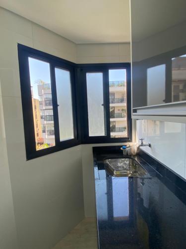 una cucina con un lavandino e finestre in una stanza di Apto a 2 min a Pé da Praia - Edificio Monte Carmel a Guarujá