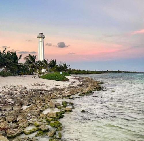 a lighthouse on the shore of a beach with the ocean at Hostal Jardin in Mahahual