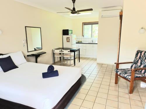 a bedroom with a bed and a chair and a kitchen at Paradise Court Holiday Units in Airlie Beach