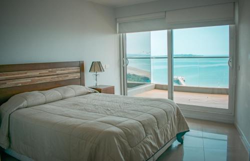 a bedroom with a bed and a view of the ocean at Alexander Beach Punta del Este in Punta del Este