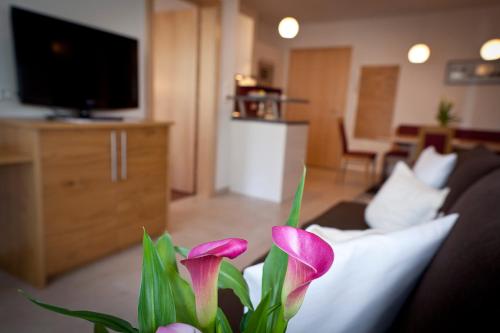 a vase with pink flowers in a living room at Alpina Appartements in Nauders