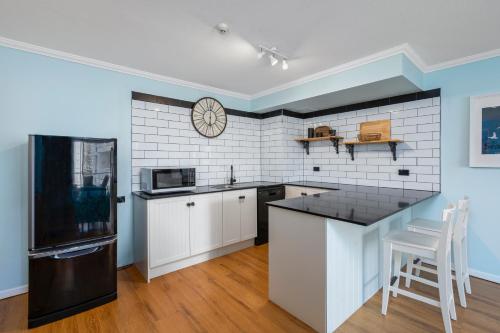 a kitchen with a black and white tile wall at Sovereign on the Gold Coast in Gold Coast